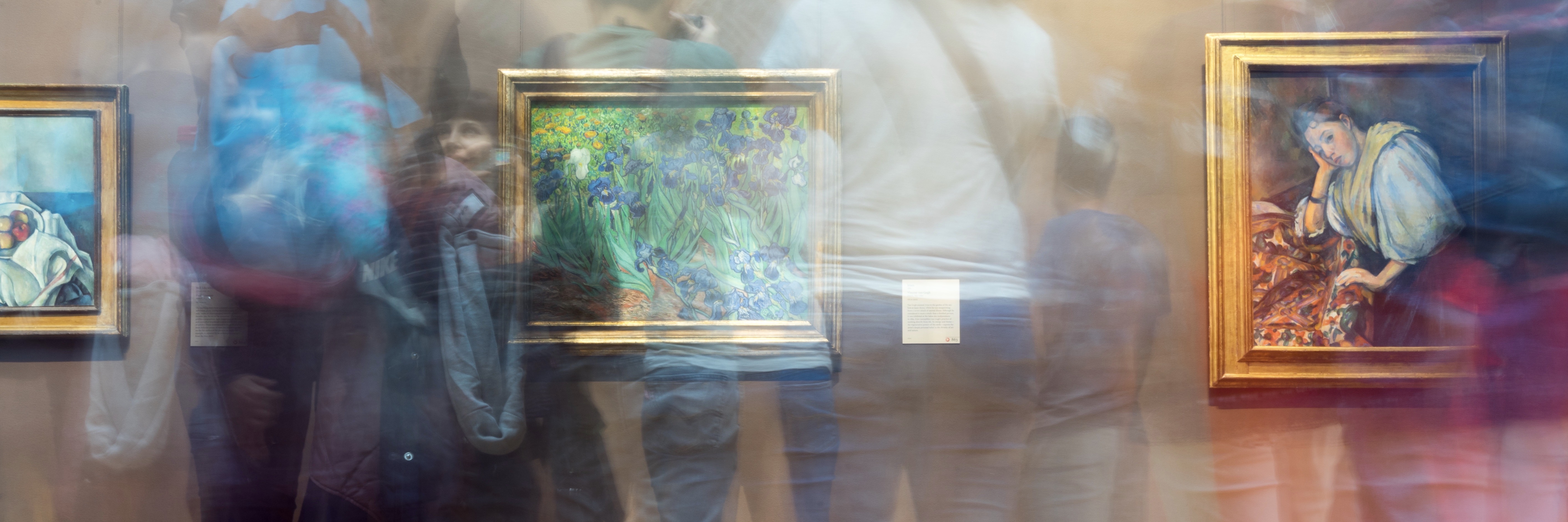 Art gallery with paintings and blurry people in the foreground