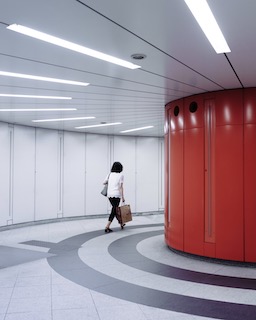 Person walking through curving hallway with red wall and striped floor